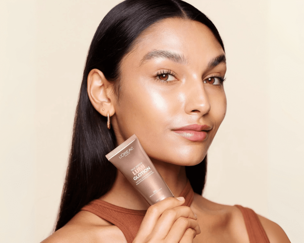 Woman with glowing, radiant skin holding L'Oréal Paris True Match Lumi Glotion Natural Glow Enhancer, perfect for a TikTok beauty finds 2025 blog on natural makeup looks.